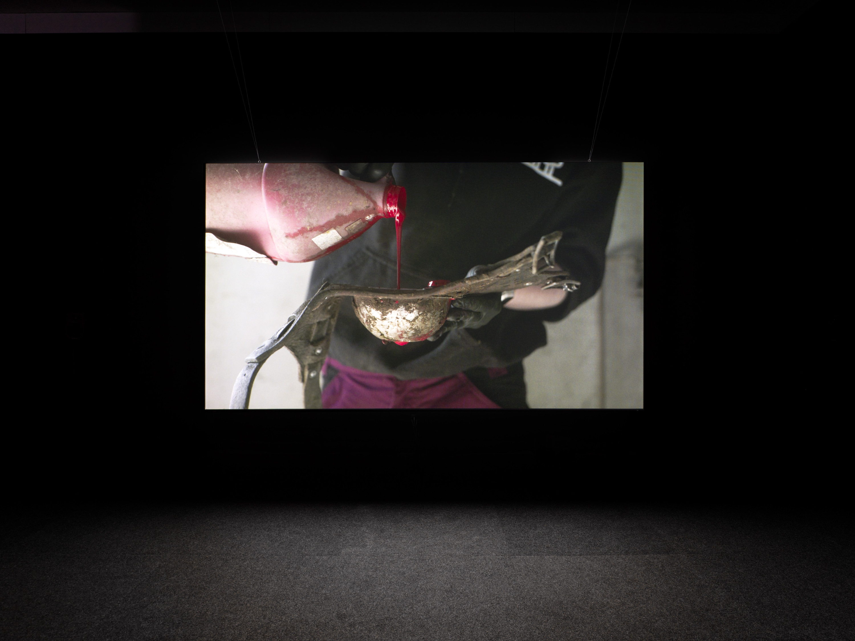 A video still with person pouring red liquid into vessel.