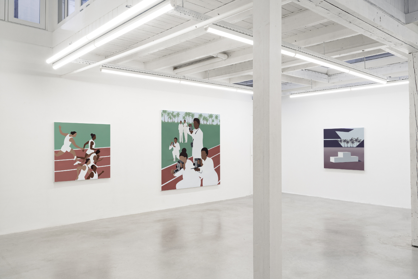 A contemporary gallery with whte walls and a polished concrete floor. In the background of the image three large paintings in bold feature bold, geometric scenes of a track race are hung. On the left five figures run a on the track. To the right a group of figures dressed in white gathers holding cameras. On an adjacent wall, an empty podium against a background of different shades of purple.